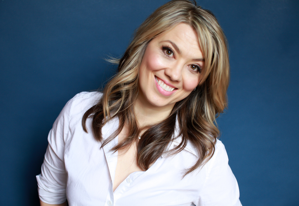 Professional headshot of a woman in a white shirt on a blue background.